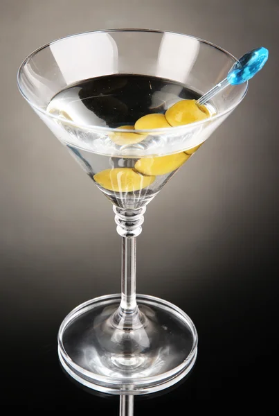 Martini mit grünen Oliven auf grauem Hintergrund — Stockfoto