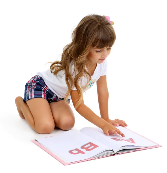 Bambina seduta sul pavimento con libro isolato su bianco — Foto Stock