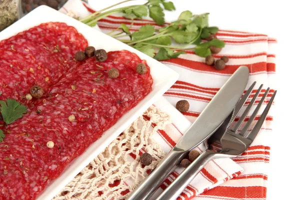 Välsmakande salami på plattan på servett isolerad på vit — Stockfoto