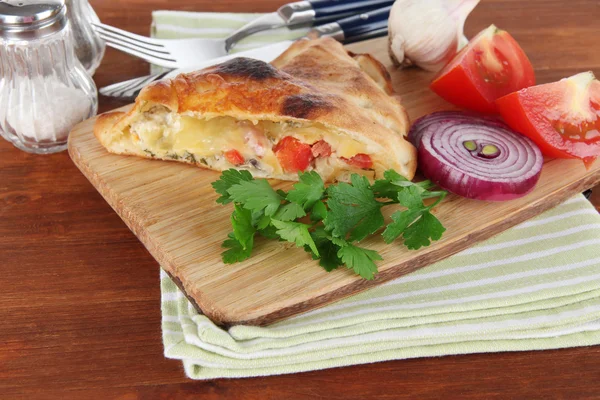 Pizza calzone trä ombord på servett på träbord — Stockfoto