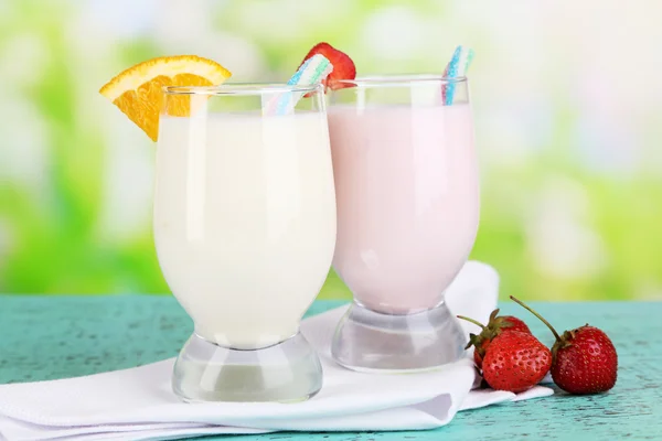 Lækker mælk ryster med orange og jordbær på træbord på naturlig baggrund - Stock-foto