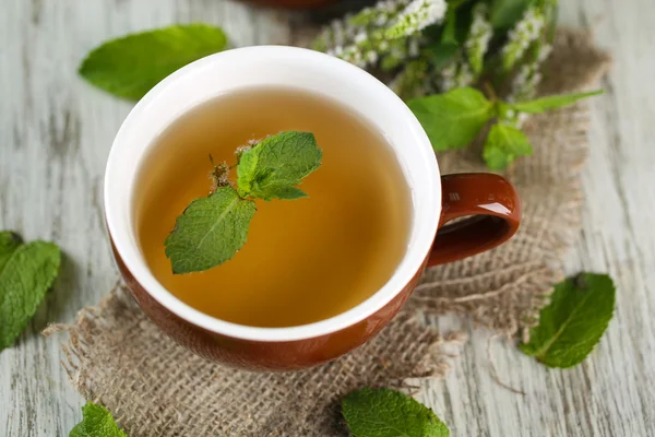 Tasse Kräutertee mit frischen Minzblüten auf Holztisch — Stockfoto