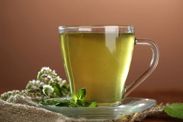 Чашка трав'яного чаю зі свіжими квітами м'яти на дерев'яному столі — стокове фото
