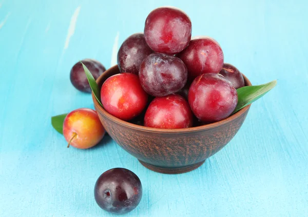 Ripe plums in bowl on wooden table close-up — Stock Photo, Image