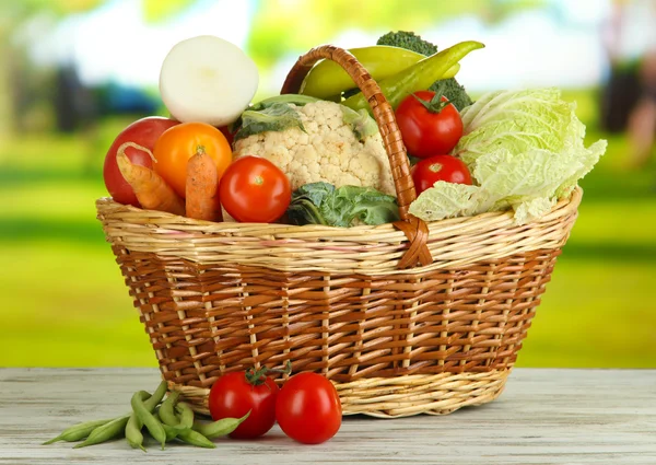 Fresh vegetables in basket on wooden table on natural background — Stock Photo, Image