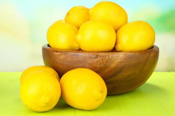 Ripe lemons in bowl on table on bright background — Stock Photo, Image