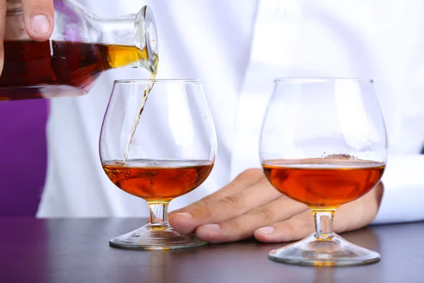 Bartender is pouring cognac into glass — Stock Photo, Image