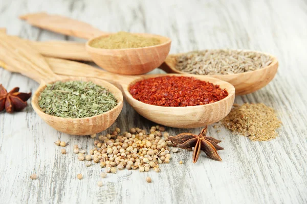 Assortment of spices in wooden spoons on wooden background — Stock Photo, Image