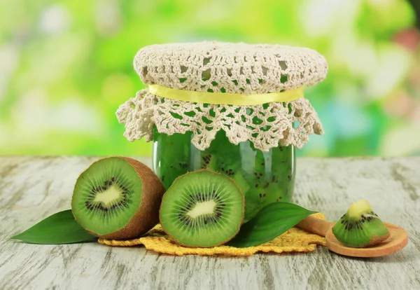 Jar of jam kiwi on wooden table on natural background — Stock Photo, Image