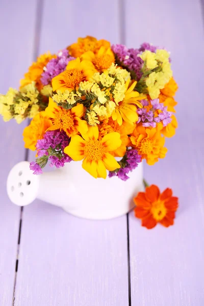 Bouquet of marigold flowers in watering can on wooden table close-up — Stock Photo, Image