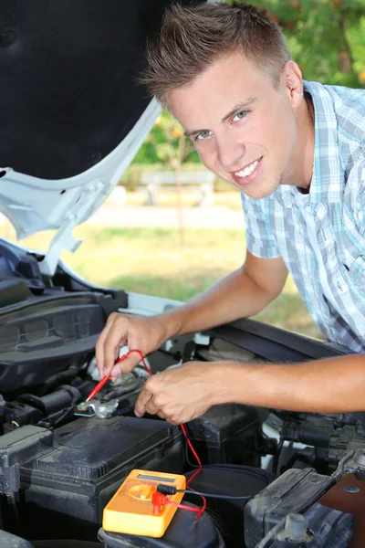 Jonge bestuurder multimeter voltmeter gebruikt om te controleren spanningsniveau in auto-accu — Stockfoto