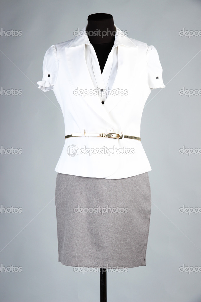 Nice blouse, white jacket and gray skirt on mannequin, on gray background