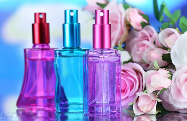 Perfume de mujer en hermosas botellas y flores — Foto de Stock