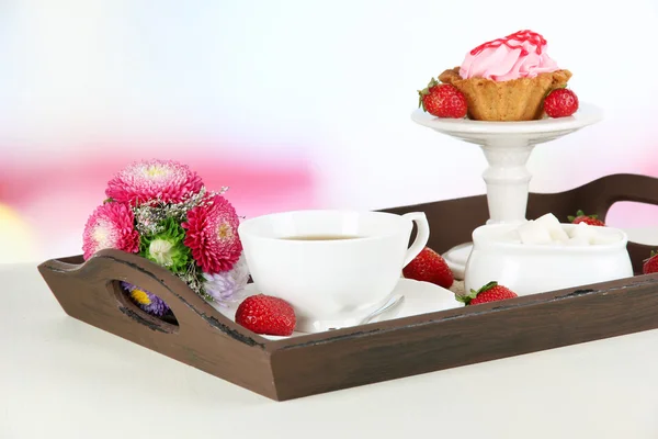 Cup of tea with cakes on wooden tray on table in room — Stock Photo, Image