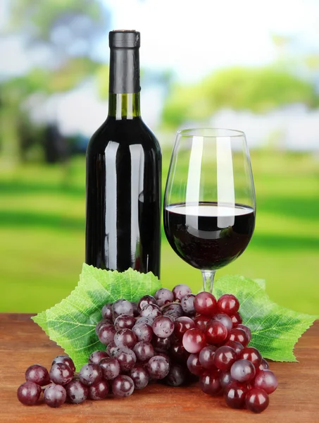 Ripe grapes, bottle and glass of wine on bright background — Stock Photo, Image