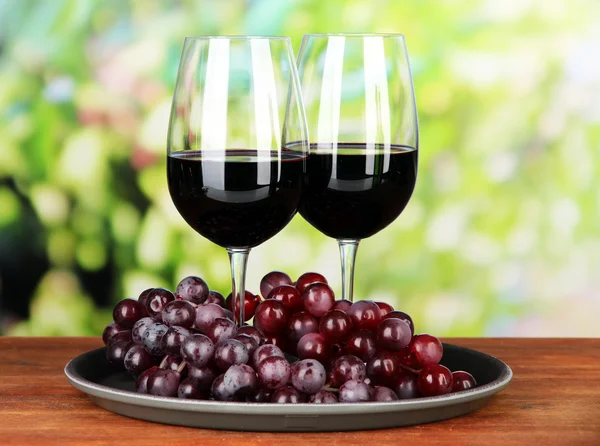 Ripe grapes and glasses of wine, on bright background — Stock Photo, Image