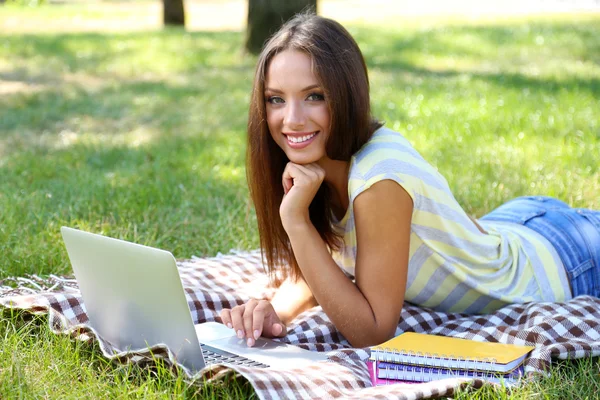Beautiful young girl with laptop in park — Stock Photo, Image