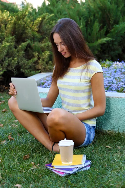 Mooi meisje met laptop in park — Stockfoto