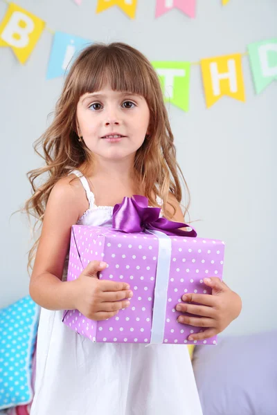 Petite fille avec cadeau dans la chambre sur fond de mur gris — Photo