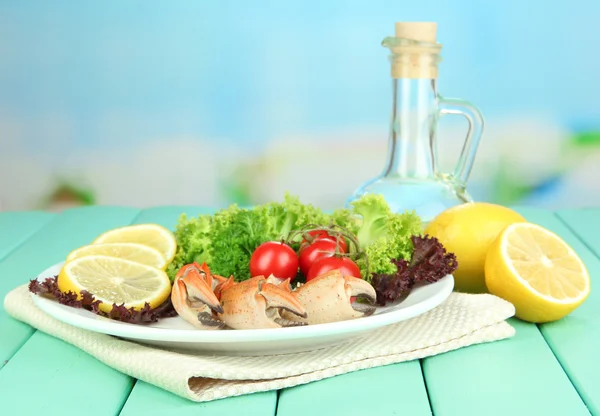 Pinces de crabe bouillies sur plaque blanche avec feuilles de salade et tomates, sur table en bois, sur fond lumineux — Photo