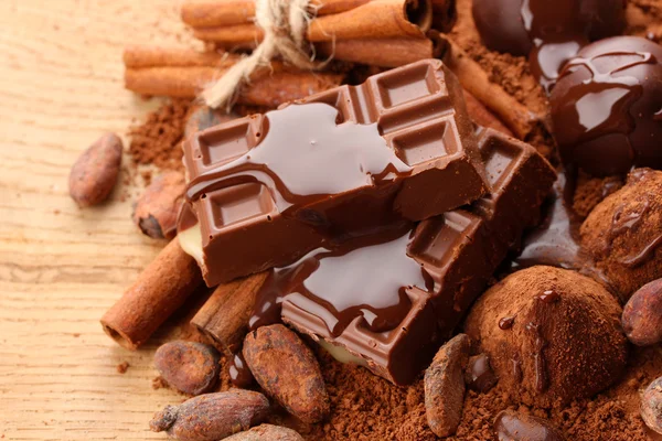 Composizione di caramelle al cioccolato, cacao e spezie su fondo di legno — Foto Stock