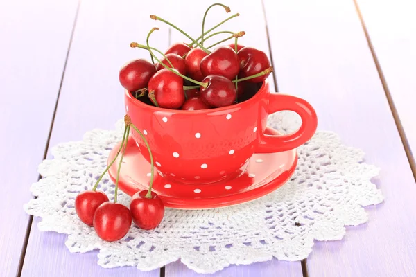 Cherry berries in cup on wooden table close up — Stock Photo, Image