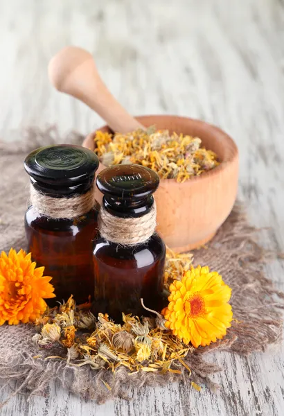 Medicin flaskor och ringblomma blommor på trä bakgrund — Stockfoto