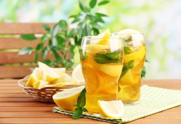 Ijsthee met citroen en mint op houten tafel, buitenshuis — Stockfoto