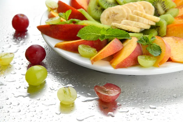 Assortment of sliced fruits on plate with drops — Stock Photo, Image