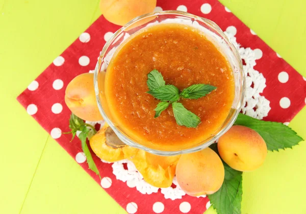 Apricot jam in glass bowl and fresh apricots, on wooden background — Stock Photo, Image