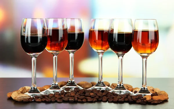 Glasses of liquors with almonds and coffee grains, on bright background — Stock Photo, Image