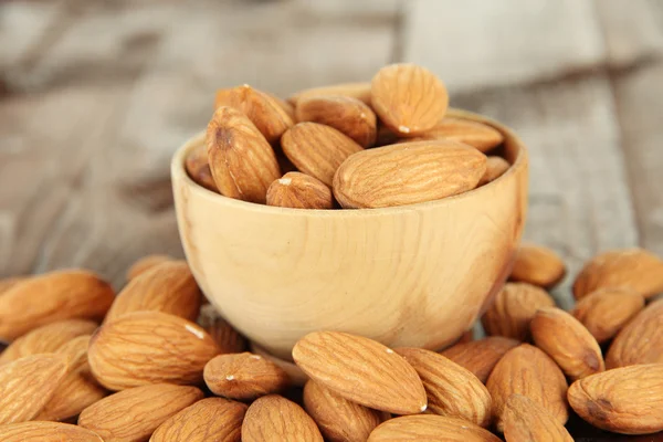 Almond in wooden bowl, on wooden background — Stock Photo, Image