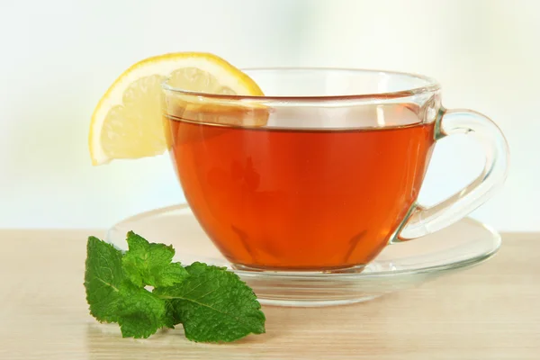 Tasse de thé avec citron sur la table sur fond clair — Photo