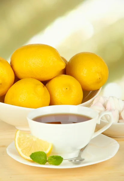 Šálek čaje s citronem na stole na světlém pozadí — Stock fotografie