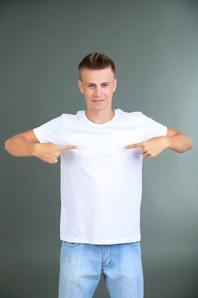 T-Shirt auf jungem Mann, auf grauem Hintergrund — Stockfoto