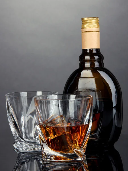 Glass of liquor with bottle, on dark background — Stock Photo, Image