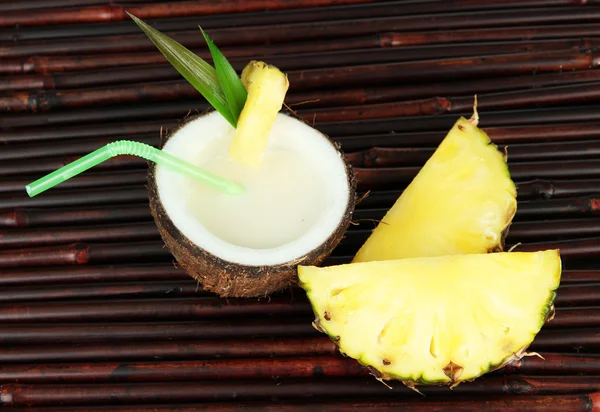 Bebida de piña colada en coco, sobre fondo de estera de bambú — Foto de Stock