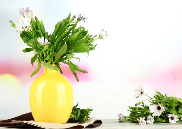 Buquê de belas flores de verão em vaso de cor, na mesa de madeira, no fundo brilhante — Fotografia de Stock