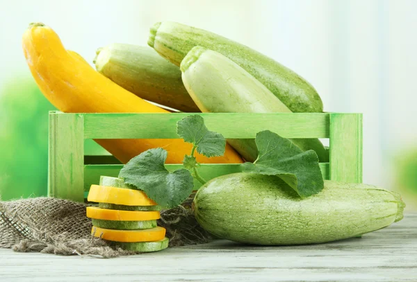 Gesneden en hele rauwe courgette in houten kist, buitenshuis — Stockfoto