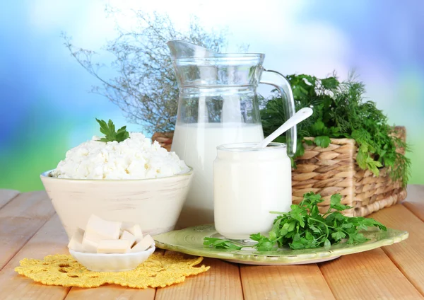 Frische Milchprodukte mit Gemüse auf Holztisch vor natürlichem Hintergrund — Stockfoto