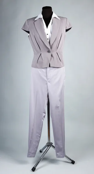 Mooie blouse, jas en grijze broek op mannequin, op grijze achtergrond — Stockfoto