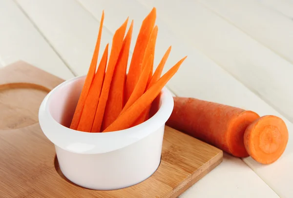 Helle frische Möhrenscheiben in Schüssel auf Holztisch in Großaufnahme — Stockfoto