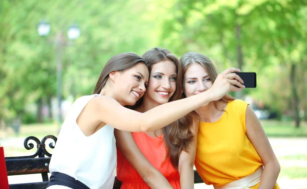 Tres hermosas mujeres jóvenes tomando fotos en el parque de verano —  Fotos de Stock