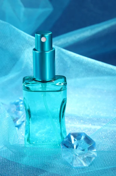 Vrouwen parfum in mooie fles op blauwe achtergrond — Stockfoto