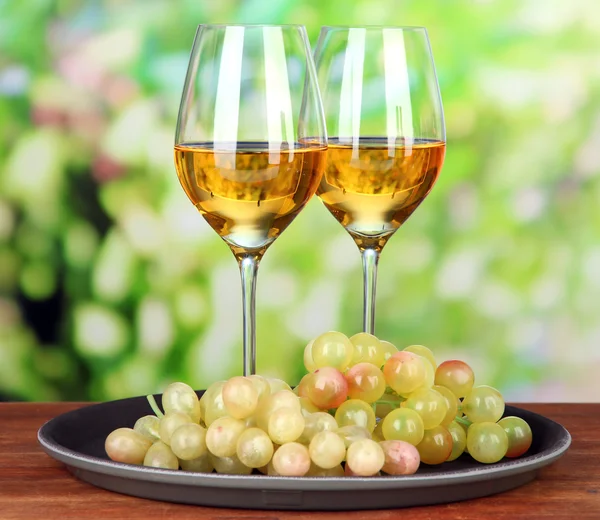 Uvas maduras y copas de vino, sobre fondo brillante — Foto de Stock