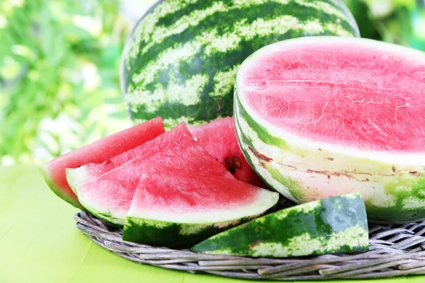 Reife Wassermelonen auf Korbblech auf Holztisch auf Naturhintergrund — Stockfoto