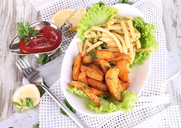 French fries and home potatoes on plate on board on napkin on wooden table — Stock Photo, Image