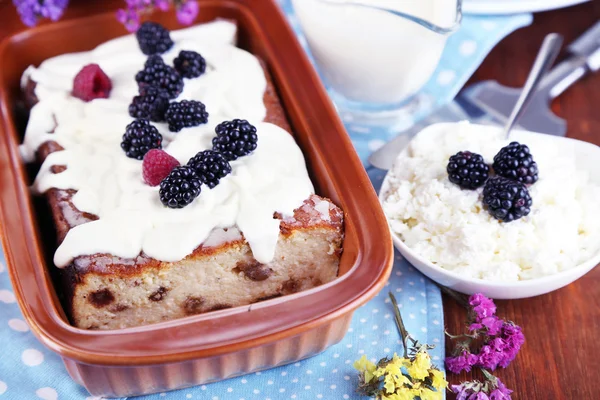 Cheese casserole with raisins in pan on napkin on wooden table close-up — Stock Photo, Image