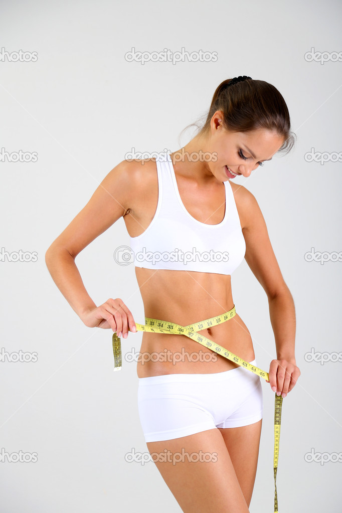 Slim girl with centimeter on gray background