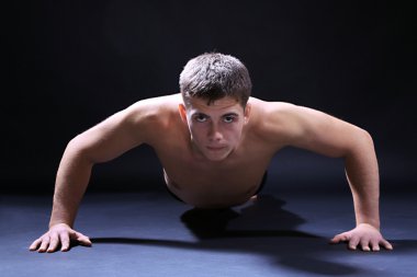 yakışıklı genç kaslı sporcu, koyu arka plan üzerinde